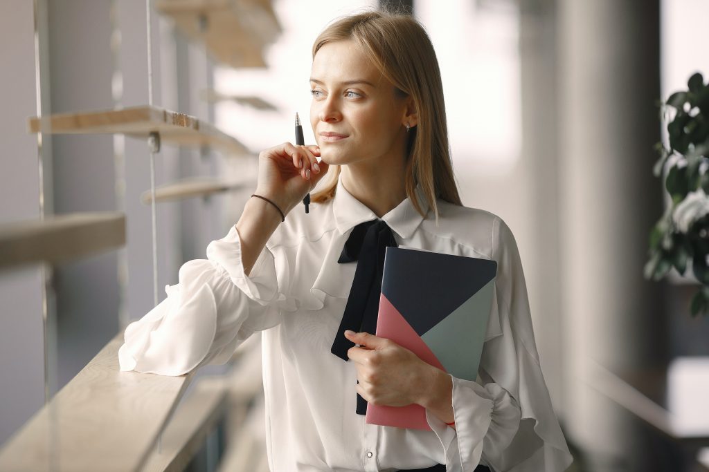 Thoughtful worker with notebook and pen in office lobby