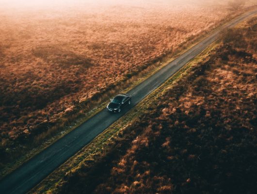 Car driving on long country road in sunset